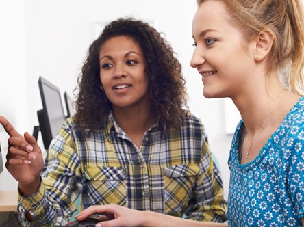 A work colleague showing a new employee something on a computer screen