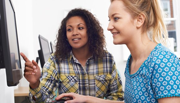 A work colleague showing a new employee something on a computer screen