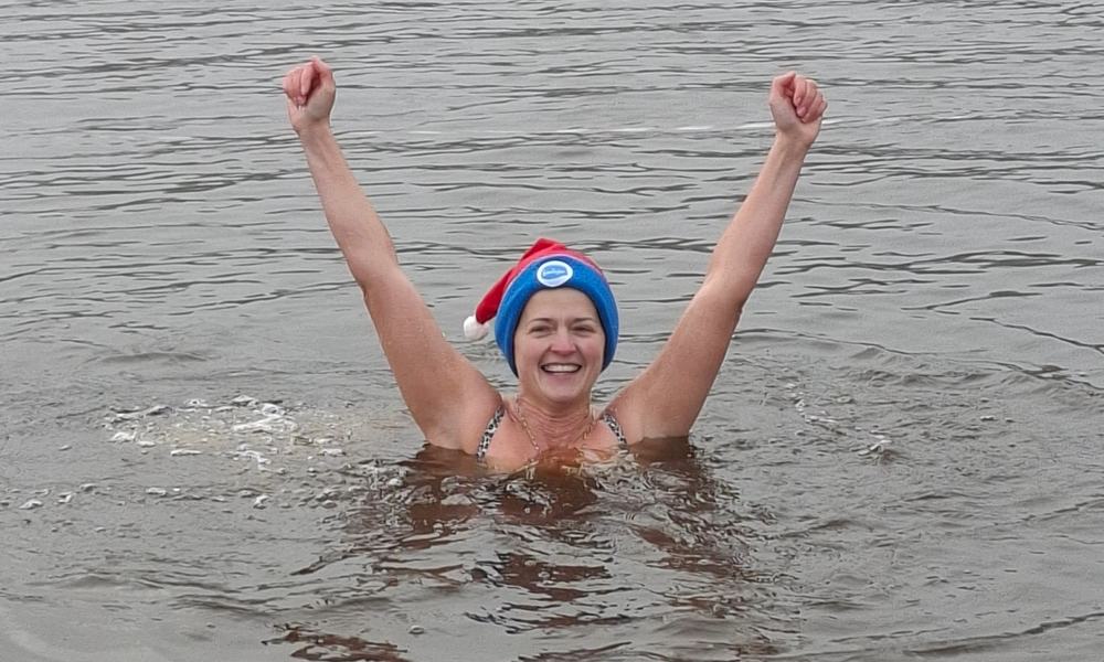 Debbie cheering as she stands in a lake in the dales as part of  Sue Ryder's Big Dip Dales 2025