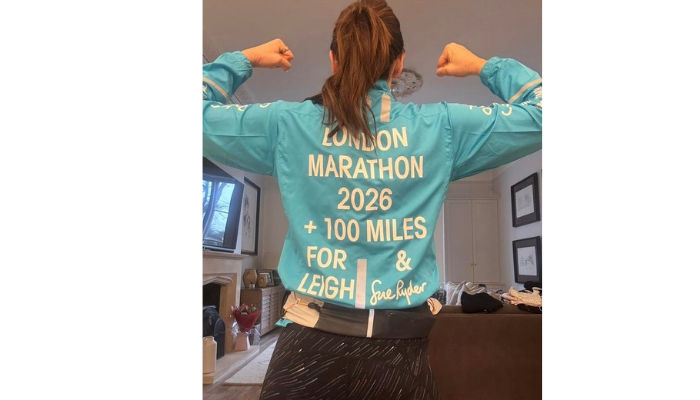 Jane posing showing back of her blue jacket with Sue Ryder running London Marathon+100-miles home