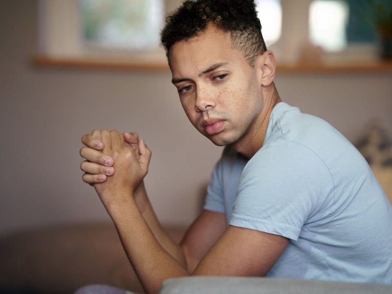 A young mixed race man looks at an empty space next to him.