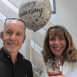 Phil and Anna smiling to camera with a happy anniversary balloon