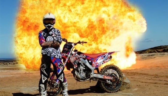 A rider and their motorcycle, in front of a massive explosion