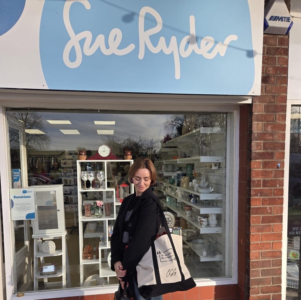 Jennifer Graham aka Charity Shop Girl stood outside of a Sue Ryder shop with the exclusive tote bag on her shoulder