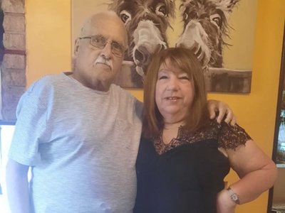 An older man and woman smiling together for a photo, showcasing their joyful expressions and close companionship.