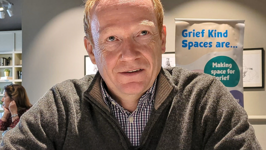 Richard sits at a table at a Grief Kind Space