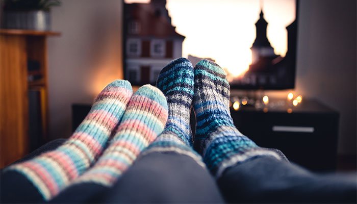 A close up of two pairs of feet in thick socks, next to each other in a living room