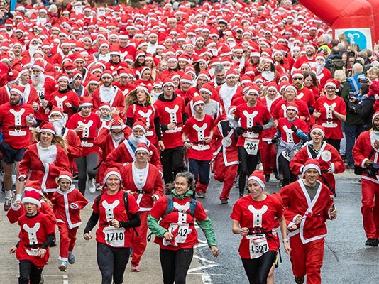 Lots of runners in Santa outfits racing down Skipton high street, with crowds cheering all around