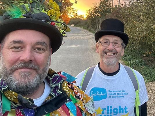 Three Starlight Hike walkers in morris dancing outfits, with the sunset behind them