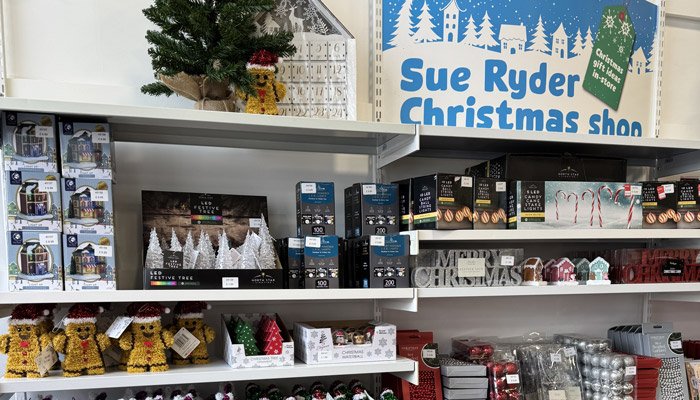 A Sue Ryder Christmas shop sign, with Christmas gifts on the shelves underneath