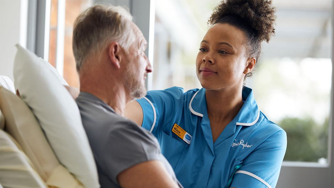 A Sue Ryder Nurse at a patient's bedside, caring for them and comforting them