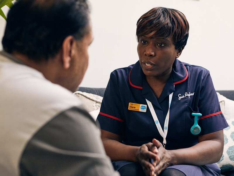 A Sue Ryder Nurse talking to a patient in their living room