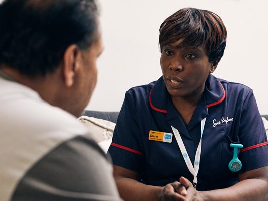 A Sue Ryder Nurse sitting opposite a patient during a home visit