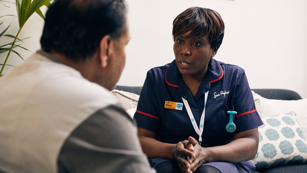 A Sue Ryder Nurse talking to a patient in their living room