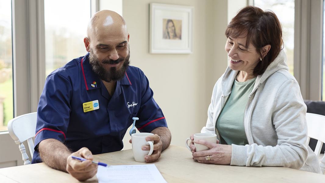 A male Sue Ryder Nurse having a cup of tea with a patient's family member