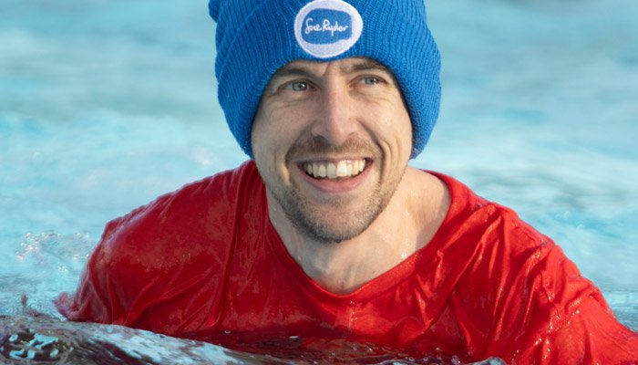 A cold water swimmer smiling, in a blue Sue Ryder winter hat