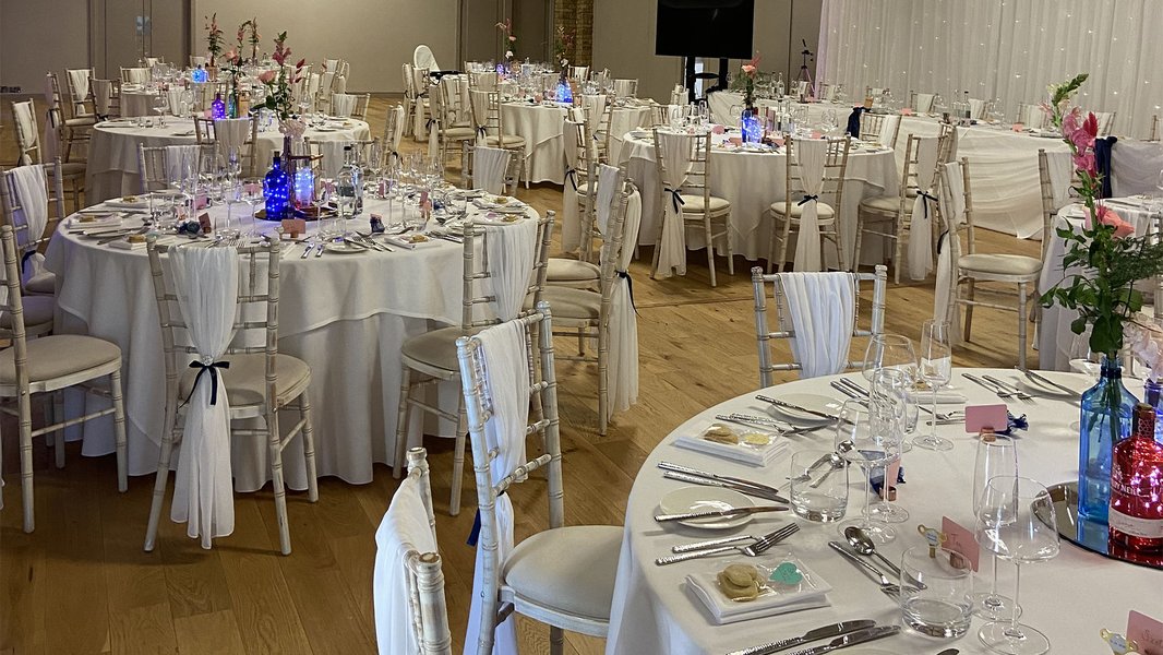 Lots of tables decorated in blue lights, with glasses, cutlery and menus on them