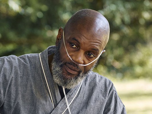 A patient in a dressing gown, with oxygen tubes in his nose to help with breathing
