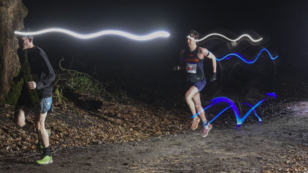 Two runners with head torches racing in the dark