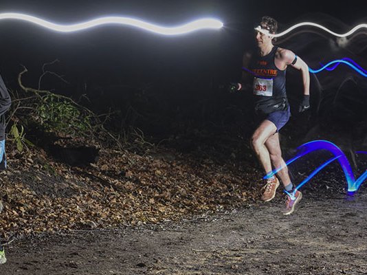 Two runners with head torches racing in the dark