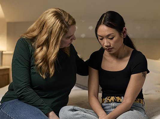 A woman consoling her grieving partner and putting her hand on their shoulder